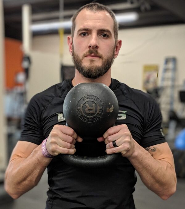 Daniel holding a kettlebell close to chest